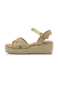 Sandale compensée beige avec des brides entrelacées, plateforme style jute et sangle de cheville ajustable. Texture de la semelle intérieure lisse.