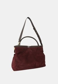 Borsa in suede bordeaux con un design strutturato, dotata di una maniglia superiore arrotondata e di una tracolla regolabile marrone.