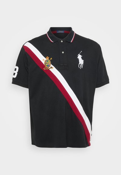 Polo shirt noir avec col, arborant une bande verticale rouge et blanche, logo brodé et détail numérique sur la manche gauche.