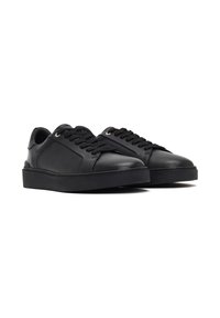 Baskets en cuir noir avec lacets plats, bout rond, détails cousus et semelle en caoutchouc texturé. Design minimaliste sans accents marquants.