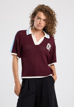 Burgundy knitted polo shirt with short sleeves, white and light blue accents on collar and sleeves, featuring a logo patch on the front.