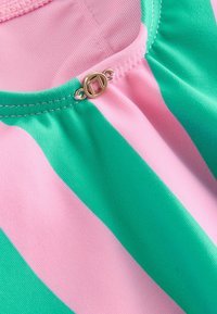 Top z paskowanej tkaniny z naprzemiennymi pionowymi paskami w kolorze różowym i zielonym. Dekolt zdobiony detalem w formie złotego zapięcia oraz marszczonym wykończeniem.