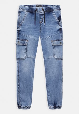 Jasnoniebieskie spodnie jogger z denimu z elastycznymi ściągaczami, sznureczkiem w pasie, skośnymi przednimi kieszeniami oraz zapinanymi na guziki bocznymi kieszeniami typu cargo.