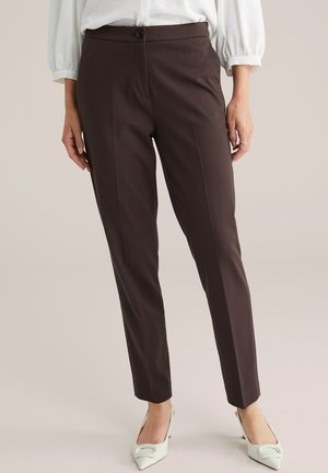Brown tailored pants with a slim fit, featuring a single button closure, textured fabric, and a smooth finish. Paired with light-colored shoes.
