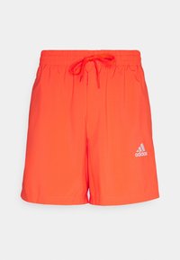 Bañador naranja brillante con cintura elástica y cordón. Presenta un logo de Adidas blanco reflectante en el lado inferior. Textura suave.