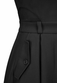 Zwarte rok met brede riem en geknoopte klepzak aan de zijkant, gemaakt van gladde stof.
