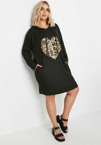 Svart hoodieklänning med ett stort hjärta i guld- och leopardmönstrad paljett-design. Har långa ärmar, en frampocket och en avslappnad passform.