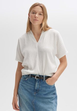 Witte, gestructureerde blouse met een v-hals en korte mouwen, gecombineerd met een denim rok en een zwarte riem. Casual, ontspannen pasvorm en ontwerp.