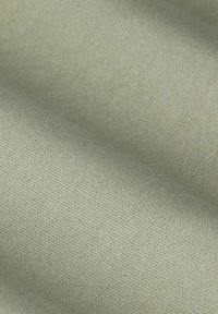Lichtgroene stof met een glad, gestructureerd oppervlak, met een fijne weving en een zachte uitstraling. Subtiele glans zonder duidelijke patronen.