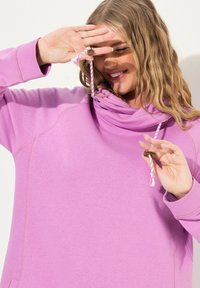 Sudadera de manga larga con capucha en suave tela de color púrpura claro, con cuello drapeado y cordón con un acento metálico decorativo.