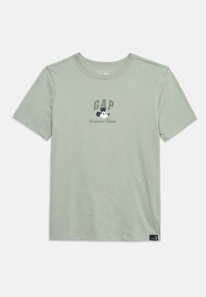 Lichtgroen T-shirt met korte mouwen en ronde hals, met een "GAP"-logo en een afbeelding van Mickey Mouse boven de tekst "American Classic" in het midden aan de voorkant.