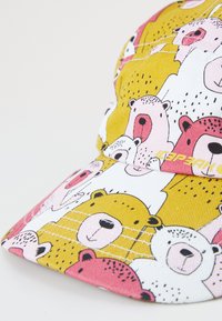 Mütze mit Bärenmuster in Gelb, Pink und Weiß. Hergestellt aus Stoff mit strukturierter Oberfläche, entworfen mit einem gebogenen Schirm.