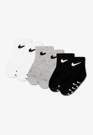 Sześć par skarpetek do kostki w kolorach białym, szarym i czarnym, każda z czarnym lub białym logo Nike swoosh blisko ściągacza.