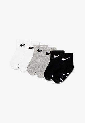 Seks par ankelsokker i hvid, grå og sort, hver med et sort eller hvidt Nike swoosh-logo nær manchet.