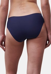 Navyblauwe zwemslip met een gladde textuur en een ontwerp met middelhoge bedekking. Heeft een gebogen tailleband en minimale stikdetails.