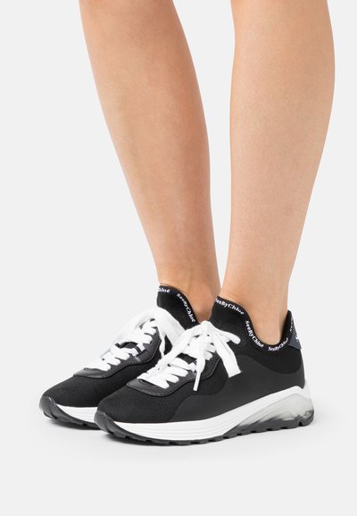 Zwarte stoffen sneakers met witte veters, een gebreide kousachtige kraag en een dikke, gestructureerde zool. Beschikt over een logo op de kraag en details op het bovenwerk.