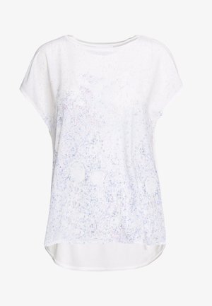 Valkoinen lyhythihainen paita, jossa on hillitty kukkakuosi pehmeissä pastellisävyissä, pyöreä pääntie ja hieman pidempi takapuu.