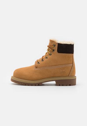 Beige Wildleder-Ankle-Boots mit einem Kunstfellkragen, braunen Akzenten, gelben Schnürsenkeln, gepolsterter Zunge und einer robusten profilierte Sohle für besseren Halt.