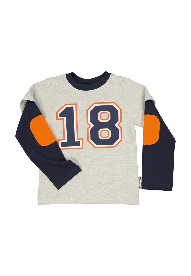 Harmaa pitkähihaisessa paidassa on tummansiniset hihat, jossa on oranssi ja tummansininen numero "18". Hihassa on myös oranssit kyynärpäänpaikat.