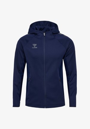 Marineblå hængetrøje lavet af blødt stof, med en fuld lynlås, sidelommer og meshpaneler for åndbarhed. Hummel-logo på brystet.
