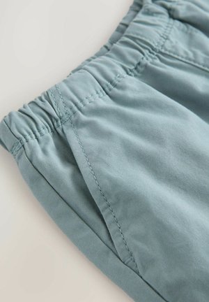 Helle blaue Shorts aus weichem Stoff, mit elastischem Bund, Seitentaschen und sichtbaren Nähten. Angenehme Textur.