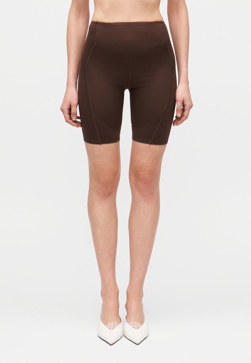 Pantalones cortos para bicicleta de talle alto en color marrón, confeccionados con tela elástica. Presentan un diseño ajustado con detalles de costuras en contraste.