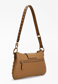 Borsa in pelle tan con hardware dorato, una tracolla removibile con borchie e una tasca anteriore con zip. Texture liscia e silhouette curva.