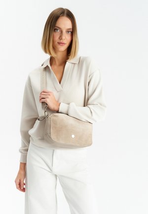 Beige ruskinds håndtaske med sølv hardware, rektangulær form, lynlås lukning og justerbar rem, præsenteret mod en hvid baggrund.