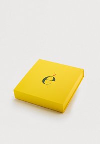 Κίτρινο τετράγωνο κουτί με λεία υφή και ένα μαύρο και κόκκινο λογότυπο στην κορυφή. Καθαρός, μινιμαλιστικός σχεδιασμός με στρογγυλεμένες άκρες.