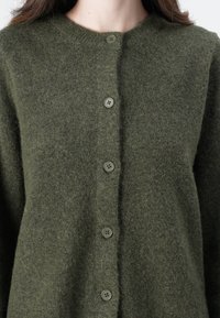 Zelený vlněný cardigan s kulatým výstřihem, který obsahuje pět kulatých knoflíků, měkkou strukturu a bezproblémový design.