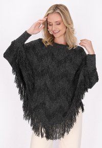 Poncho negru cu franjuri, având un design tricotat texturat, cu gât rotund și mâneci largi, care se lasă ușor pe corp.