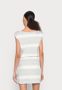 Bílé šaty s horizontálními modrými pruhy a tečkovanými vzory, krátké rukávy se sklady, přiléhavý střih a rovný spodní lem.