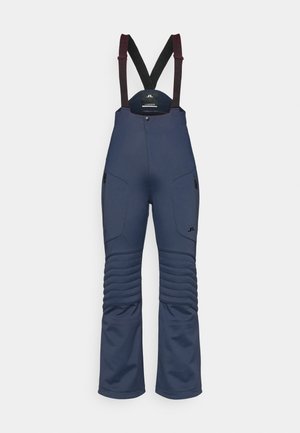 Tumed suusatamisülikonnad reguleeritavate mustade ja burbonaadi rihmadega, lukuga taskud, soonikkoes põlvede detailid ja istuv talje.