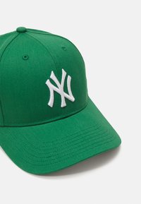 Zöld baseball sapka, amely szövetből készült, strukturált koronával és ívelt napellenzővel rendelkezik, a elülső részén fehér hímzett logó található.