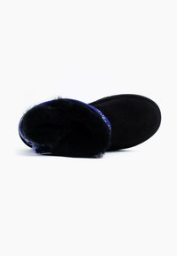 Zapatillas de ante negro con un interior de felpa y un puño de diseño azul. Forma redondeada, textura suave y suela plana de goma para mayor comodidad.
