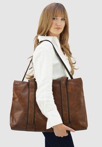 Bruine leren tote bag met een gestructureerd ontwerp, dubbele handvatten bovenaan en contrasterende stiksels. Gladde textuur met minimale accenten.