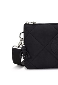Svart kviltad tyg crossbody-väska med silverdetaljer, som har en liten svart karaktärsberlock och en justerbar rem.