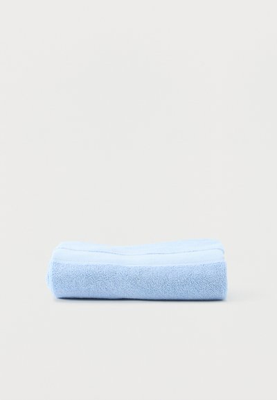 Φωτεινό γαλάζιο διπλωμένο πετσέτα μικροϊνών σε απλό ανοιχτό γκρι φόντο.