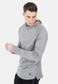 Leichter, melierter grauer langärmeliges Hoodie mit einer vorderen Kängurutasche, Kapuze und schmal zulaufenden Ärmeln. Mit einem Logo am Saum.