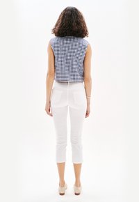Top senza maniche in gingham blu e bianco, pantaloni bianchi a vita alta, lunghezza cropped, abbinati a tacchi beige chiaro, mostrati da dietro.