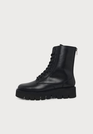 Bottine noire en cuir à lacets, avec fermeture éclair latérale et épaisse semelle plateforme profondément rainurée.