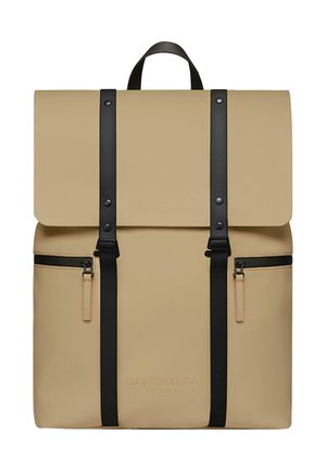 Beige rygsæk lavet af holdbart materiale, med en fold-over flap, sorte stropper og accenter, samt to lynlåslommer foran.