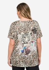 Camiseta con estampado de leopardo que cuenta con un gran gráfico de tigre en la parte posterior. Tejido suave, corte holgado y mangas cortas con un escote amplio.