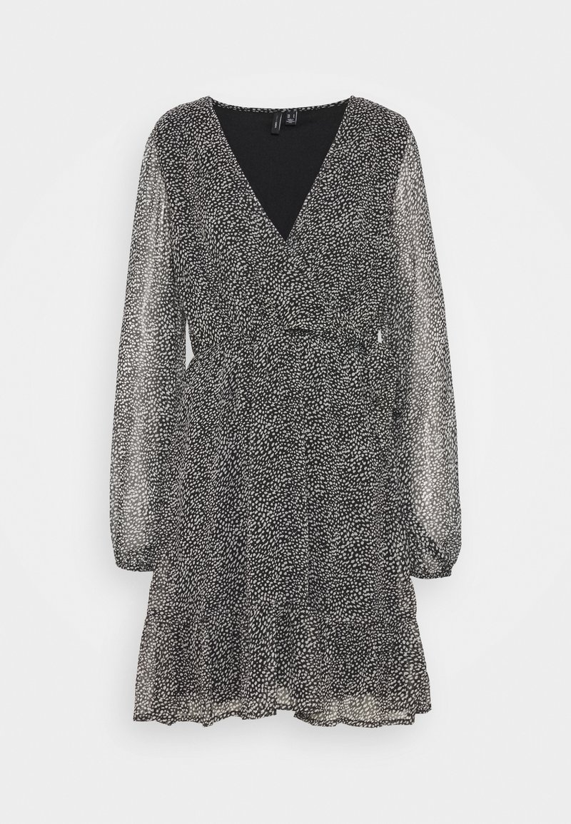 Robe à manches longues à pois noir et blanc avec encolure en V, taille cintrée et jupe à volants sur fond uni.