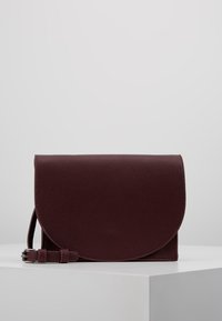 Borsa a pochette in pelle borgogna con patta arrotondata, superficie texturizzata, tracolla regolabile e design minimalista. Compatta e funzionale.
