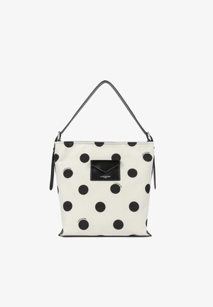 Sac cabas blanc avec de grandes pois noirs et une poche avant noire, doté d'une seule bandoulière noire.