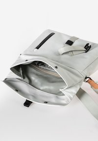 Hellgraue Umhängetasche mit einem oberen Reißverschluss und einer Vordertasche. Weiches, glattes Material und verstellbarer Gurt mit einem Lederakzent. Innenfutter.