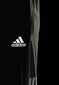 Svarta sportshorts i glatt material med en vit Adidas-logga och tre vertikala vita ränder på den nedre sidan.