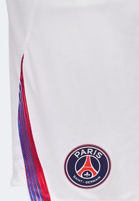 Άσπρες αθλητικές βερμούδες με λογότυπο Paris Saint-Germain και κόκκινες και μπλε κάθετες ρίγες στο πλάι.