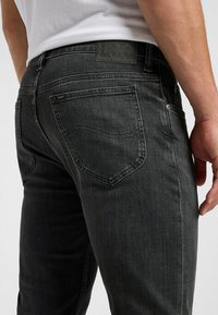 Donkergrijze jeans van denim, met een strakke pasvorm, subtiele wassing en een leren tailleband met textuur en een geperst logo.